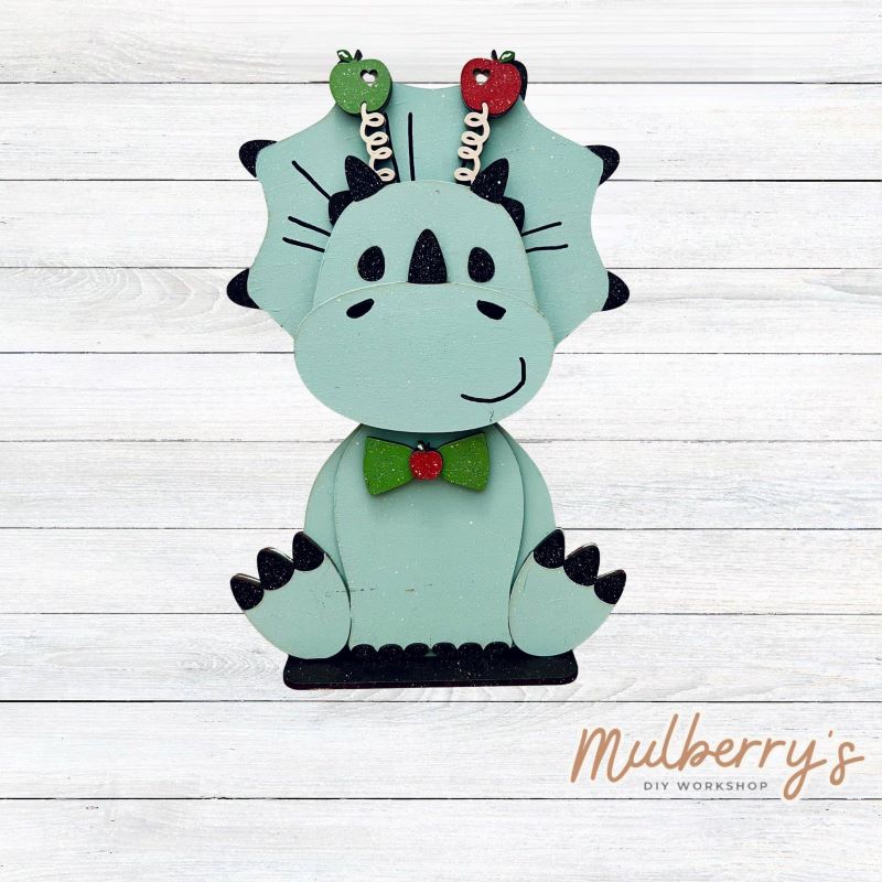Our triceratops dinosaur is super cute! It's approximately 11.5" tall and can be paired with your favorite seasonal/holiday insert.
This set includes the interchangeable triceratops dinosaur and your choice of apple inserts:
-Headband with Bow Tie
-Apple
Please note that different inserts fit each type of dinosaur base differently. For our interchangeable triceratops, we recommended pairing it with the apple insert.