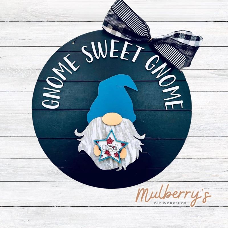 This sweet little fella will make you smile each season and holiday. Simply swap out his hands to create a brand new door hanger! The door hanger is approximately 18-inches in diameter and comes with or without greenery on the backer. Includes Gnome Sweet Gnome door hanger with July 4th insert.