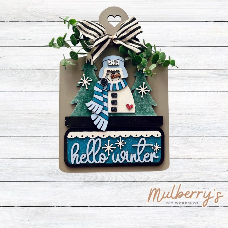 This Interchangeable Breadboard measures roughly 9" wide & 13.5" tall.
This project can easily be changed out for holidays, seasons and other themes. Because the breadboard leans back with the use of an easel, no magnets or adhesive hook and loop is needed.
The set includes the breadboard and winter inserts.
