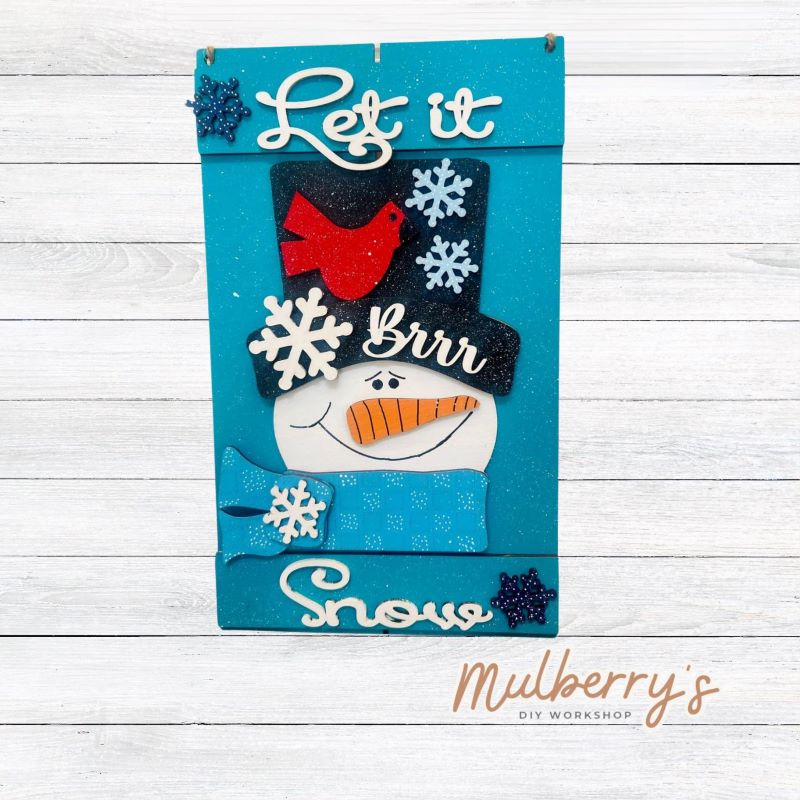 Brrr..let it snow! Our let it snow mini door hanger welcomes winter with a snowman and cardinal. Approximately 14" tall by 8" wide.