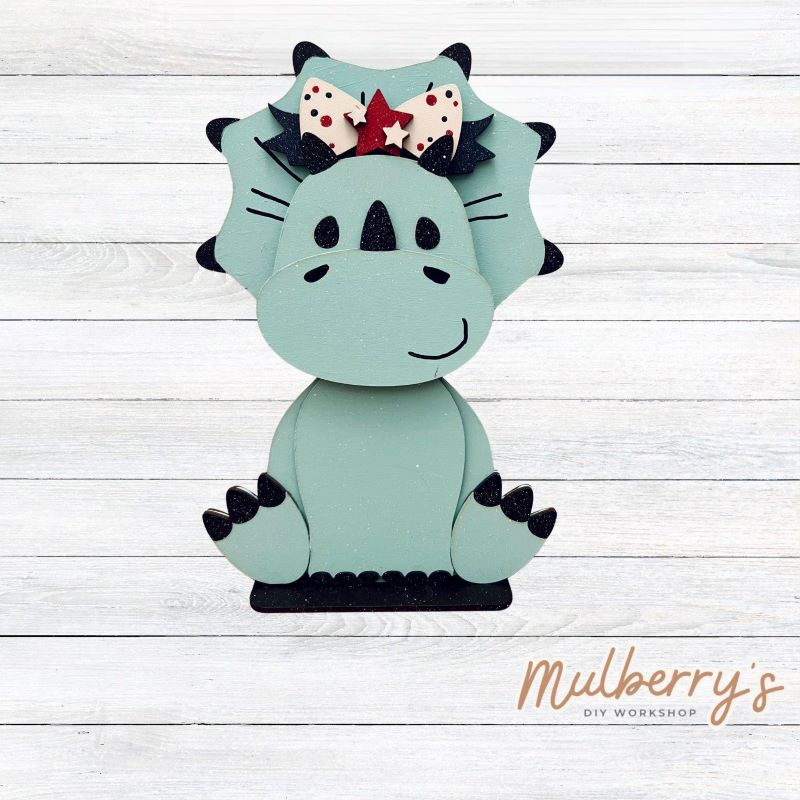 Our triceratops dinosaur is super cute! It's approximately 11.5" tall and can be paired with your favorite seasonal/holiday insert.
This set includes the interchangeable triceratops dinosaur and your choice of July 4th inserts:
-Headband with Bow Tie
-Headbow
-Statue of Liberty Spike Hat
Please note that different inserts fit each type of dinosaur base differently. For our interchangeable triceratops, we recommended pairing it with the statue of liberty spike hat insert.