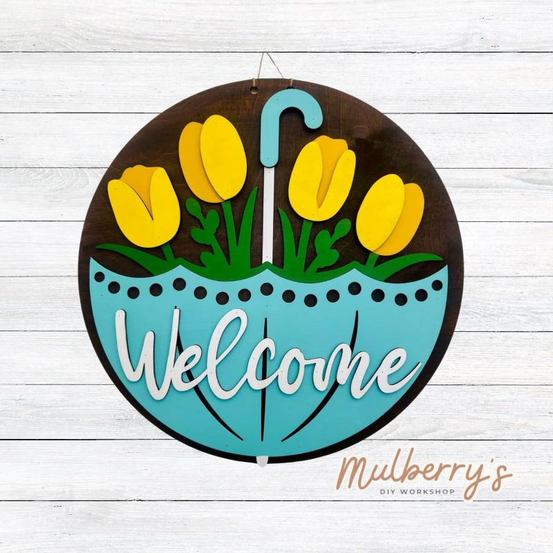 Welcome Spring into your home with this quirky 18 inch door hanger featuring a gigantic umbrella with tulips peeping from the inside. Hang it on your front door to greet guests with a playful touch. Perfect for adding a unique touch to your seasonal decor.