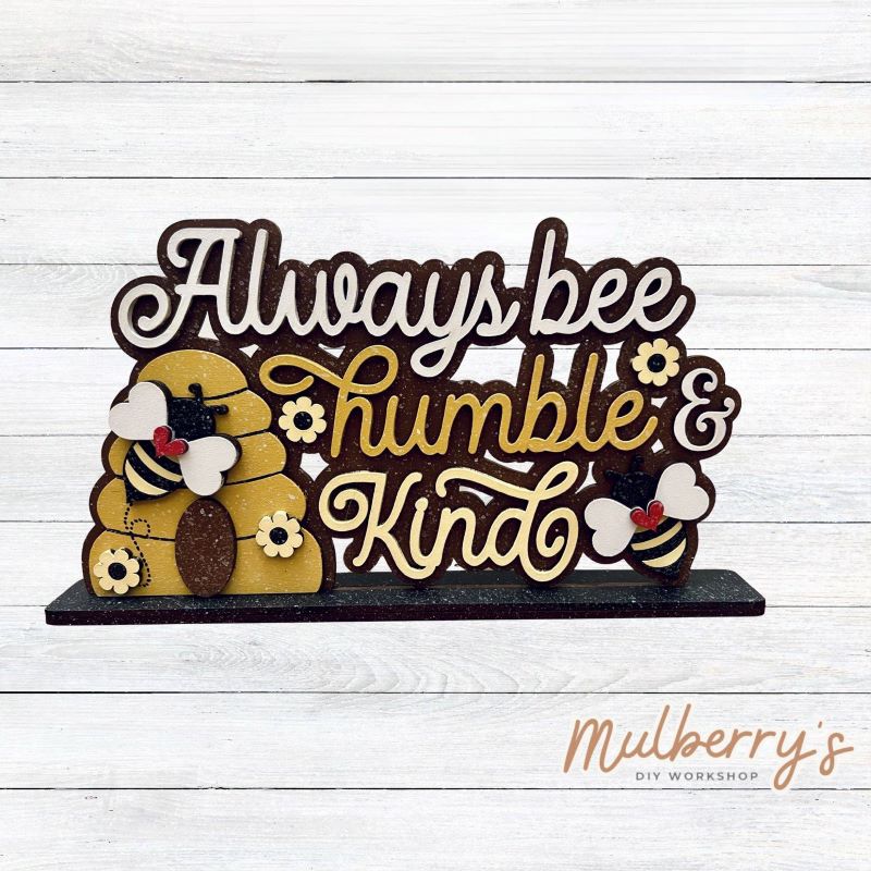 Always bee humble & kind with our latest bee-themed shelf sitter! Approximately 9" wide by 6" tall. Includes stand.