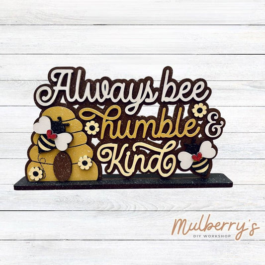 Always bee humble & kind with our latest bee-themed shelf sitter! Approximately 9" wide by 6" tall. Includes stand.