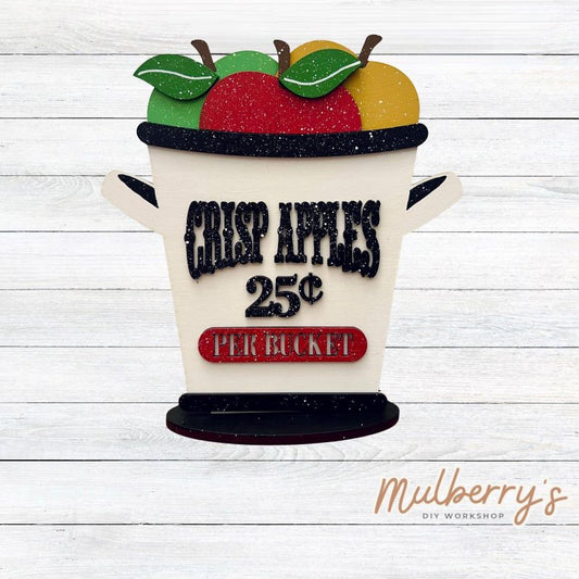 Apple picking season is the best! After going to your local orchard, come paint our apple bucket shelf sitter! It's approximately 9.5" wide by 10" tall and includes a stand.