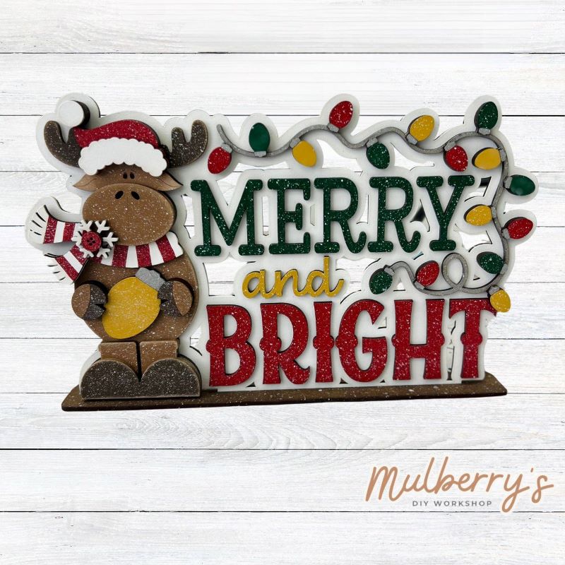 Celebrate the joy of the holiday season with our new Christmas reindeer merry & bright shelf sitter! This cutie measures approximately 7" wide by 9" tall. Includes a stand.