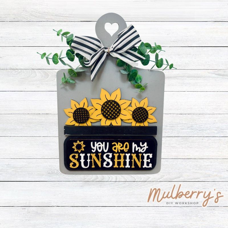 This Interchangeable Breadboard measures roughly 9" wide & 13.5" tall.

This project can easily be changed out for holidays, seasons and other themes. Because the breadboard leans back with the use of an easel, no magnets or adhesive hook and loop is needed.

The set includes the breadboard and sunflower inserts.